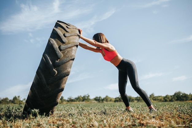 Fitness woman in cross fit training lifting a wheel as part of her exercise routine cross fit traini