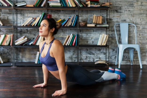 Fitness woman doing cobra pose during yoga workout on floor at home