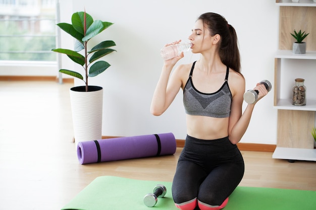 Fitness woman drinking water from bottle after workout