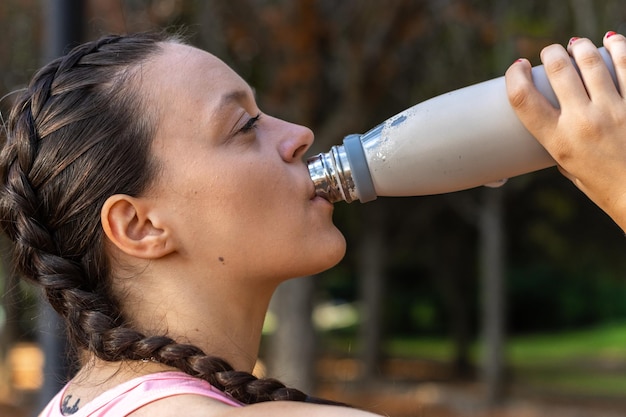 Fitness woman drinking water from a bottle after workout