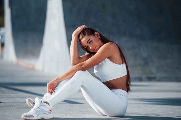 Fitness woman having a rest near the lake at daytime. Beautiful sunlight.