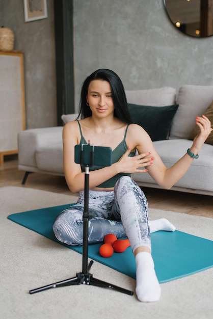 Fitness woman teacher communicates with her students via video broadcast and does exercises with them