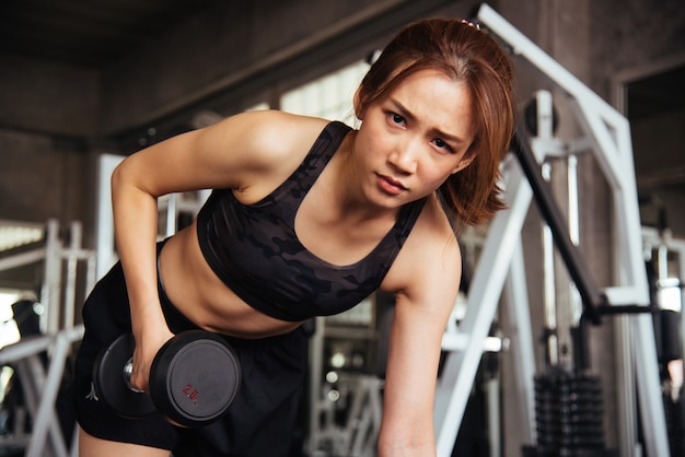 Fitness woman in training exercises with dumbbells.