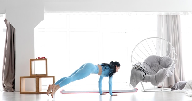 Fitness workout at home. Healthy fit young woman doing exercise in the living room.