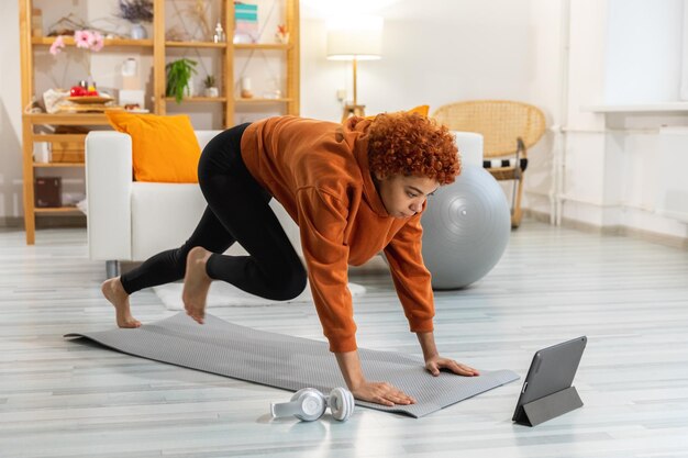 Fitness Workout training Young healthy fit african girl doing sports exercise on yoga mat on floor at home Athletic woman in sportswear have training workout for weight loss Sport and fitness