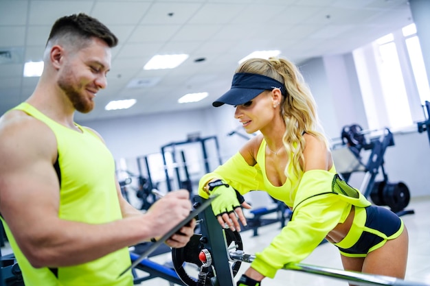 Fitness young couple in modern gym Fit training lady and guy at gym