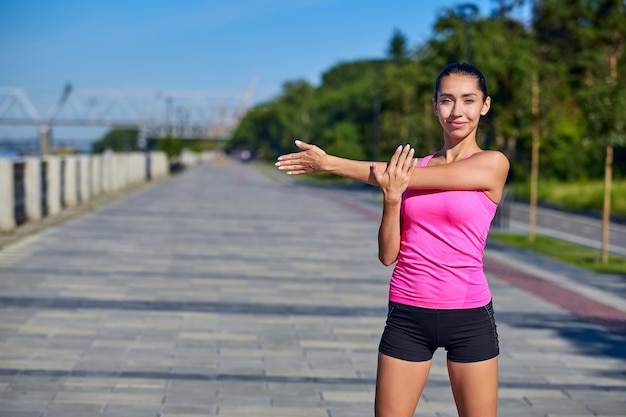 Fitness young woman stretching hands after run outdoors after run