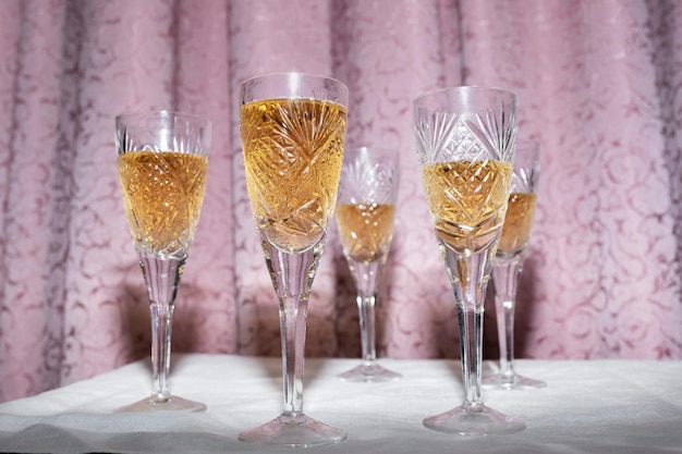 Five crystal glasses with champagne on a curtain background nineties style concept