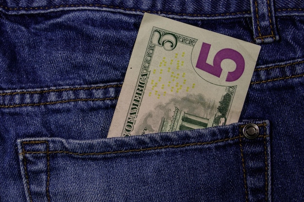 Five dollars banknote in the pocket of blue jeans