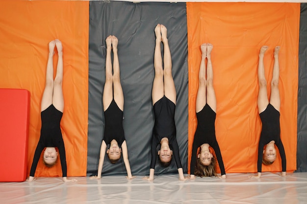 Five little girls doing gymnastic moves on a stage