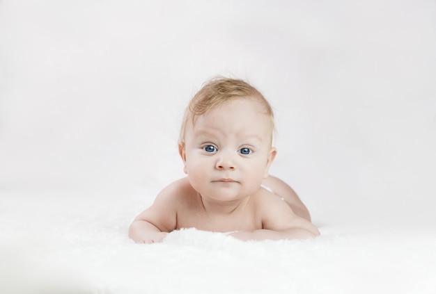 Five-month-old blond boy with blue eyes lies on his stomach