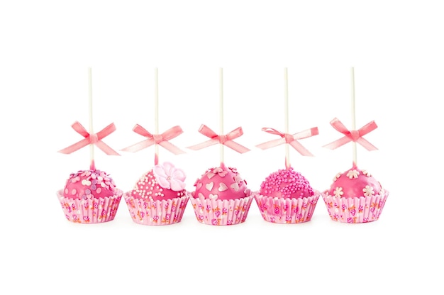 Five romantic pop cake with pink frosting decorative sprinkles and pink ribbons isolated on white background