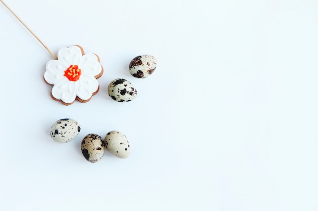 five speckled quail eggs and gingerbread in the form of a flower on a white background Easter concept top view