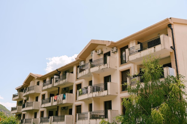 Fivestory hotel with terraces and green trees against a blue sky