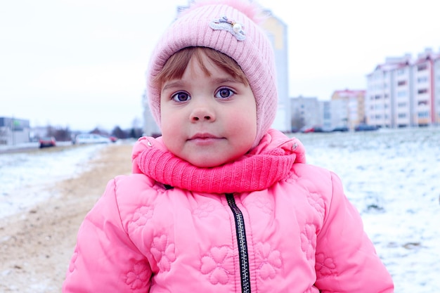 A fiveyearold girl in pink clothes walks alone on a city street on a winter day