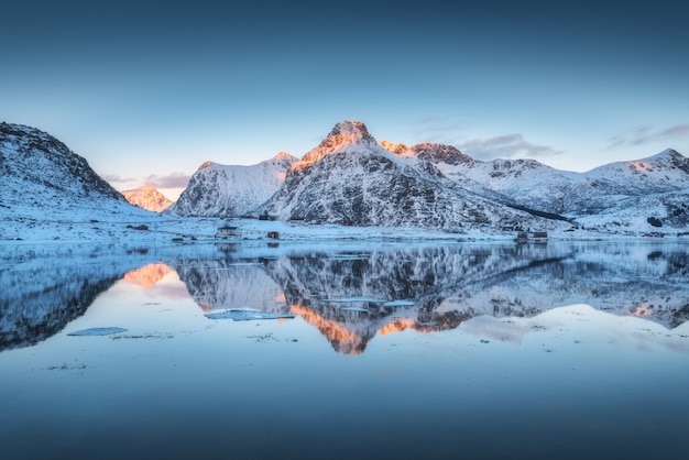 Fjord with reflection in water, snowy mountains at sunset