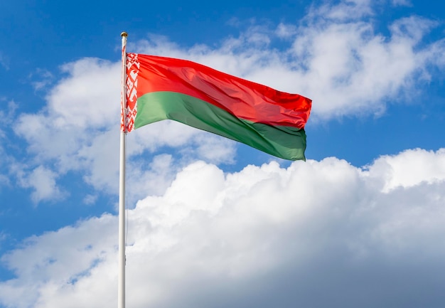 Flag of Belarus on flagpole waving against blue sky