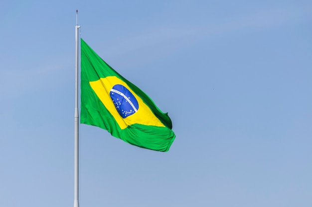 Flag of Brazil fluttering in the blue sky Order and Progress in Portuguese Brazilian flag