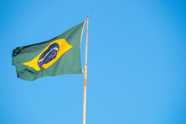 Flag of Brazil outdoors with a beautiful blue sky in the background in Rio de Janeiro Brazil.