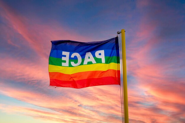 The flag in the colors of peace flutters against the backdrop of a dramatically spectacular red sky Symbol of peace in this time of war pro concordia labor