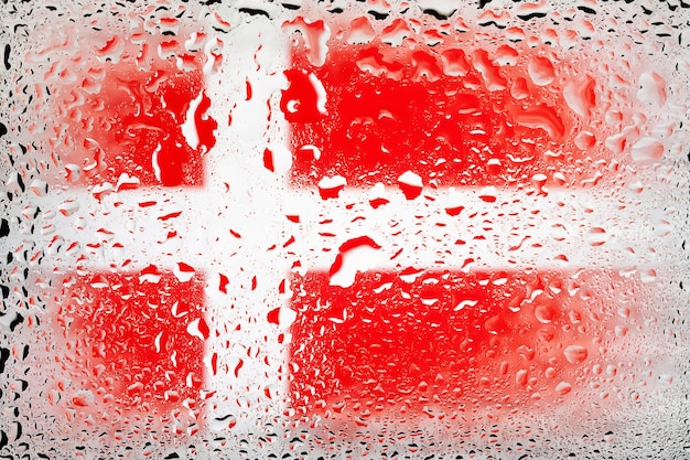 Flag of Denmark Denmark flag on the background of water drops Flag with raindrops Splashes on glass