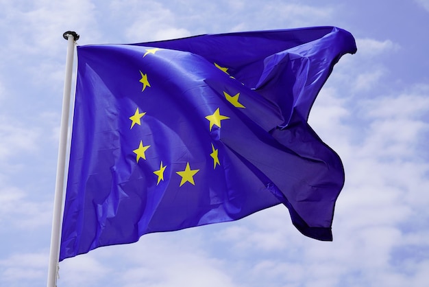 Flag of European Union EU in cloud sky in mast with blue background and yellows stars