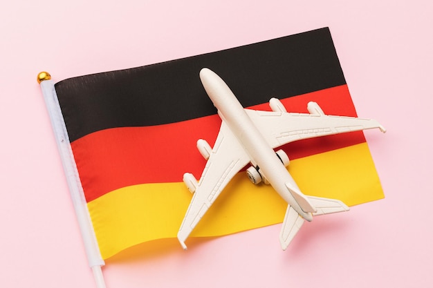 Flag of Germany and a toy plane on a pink background, concept on the theme of travel to the country