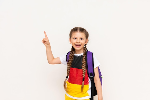 The flag of Germany on the Tshirt of a little girl A beautiful child with pigtails points with his index finger at your advertisement on a white isolated background Language courses for children