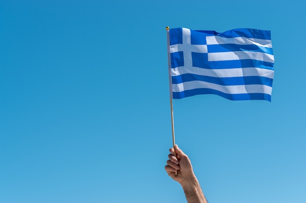 Flag of Greece in human hand on sky background