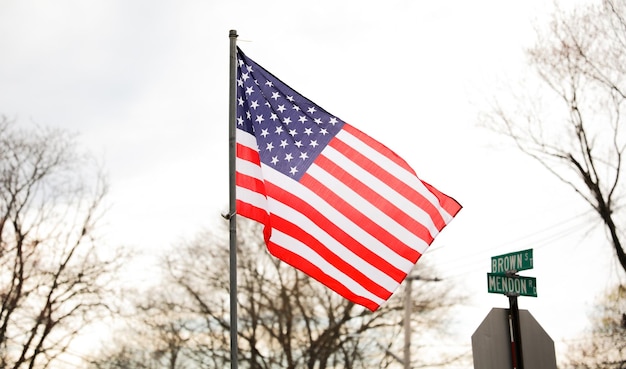 A flag is flying in front of a green street sign.