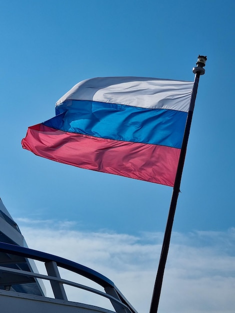 The flag of the Russian Federation against the background of a blue sky