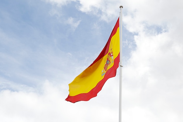 Flag of Spain against cloudy blue sky