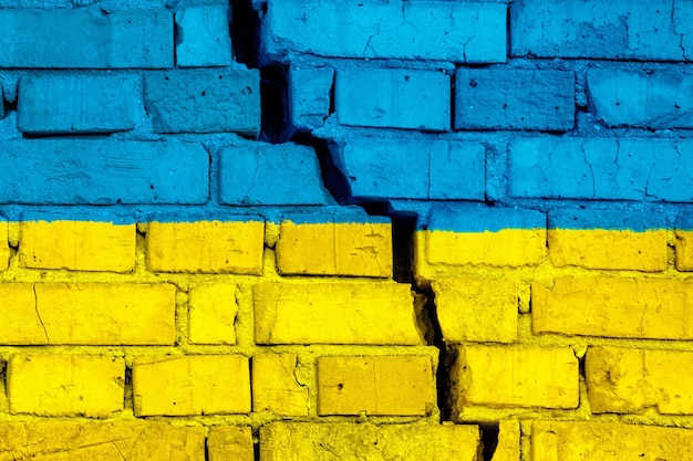 Flag of Ukraine on the brick wall with big crack in the middle Destruction and separatism concept