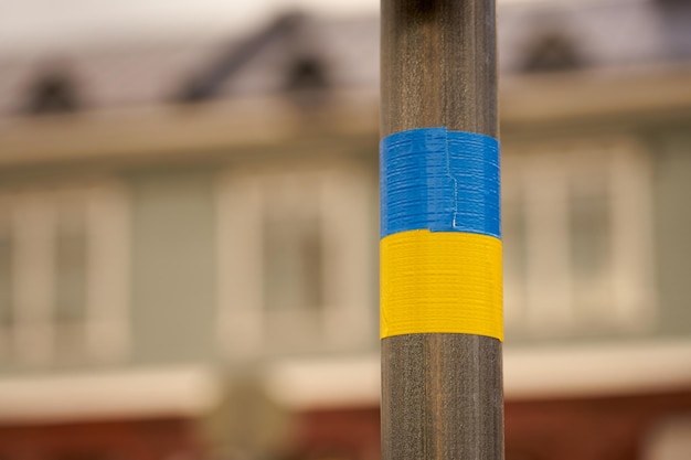 The flag of Ukraine is made of insulating tape on a pole from a road sign