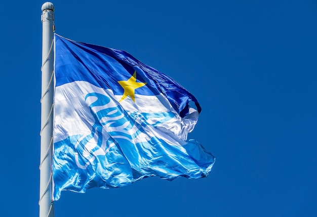 The flag of the Zenit football team on a flagpole fluttering in the wind against the sky