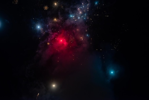 Flashes of fireworks in blue and red smoke in the night sky