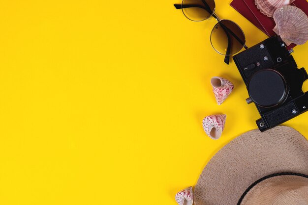 Flat accessories for travelers on a colored background with a straw hat, camera, and sunglasses. Copy space