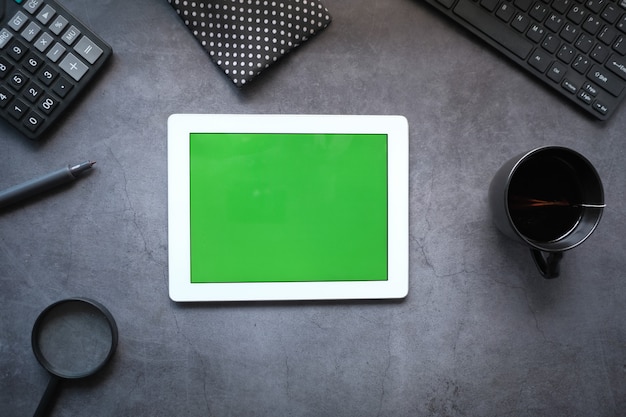 Flat composition of digital tablet and office stationary on black desk.