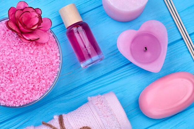 Flat lay accessories for body care on blue wooden desk. Candle with lotion bottle and soap.