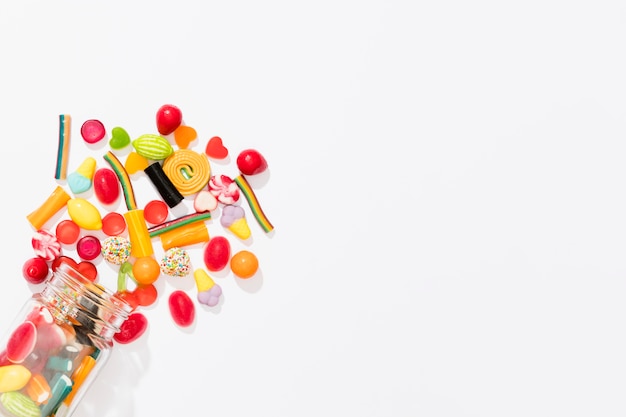 Flat lay assortment of colorful candies on white background with copy space