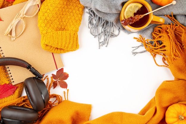 Flat lay autumn composition with fall leaves, hot cup of tea and a warm woolen orange sweater