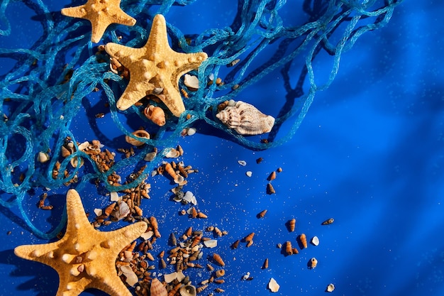 Flat lay background with starfish seashells on blue water texture with sunlight