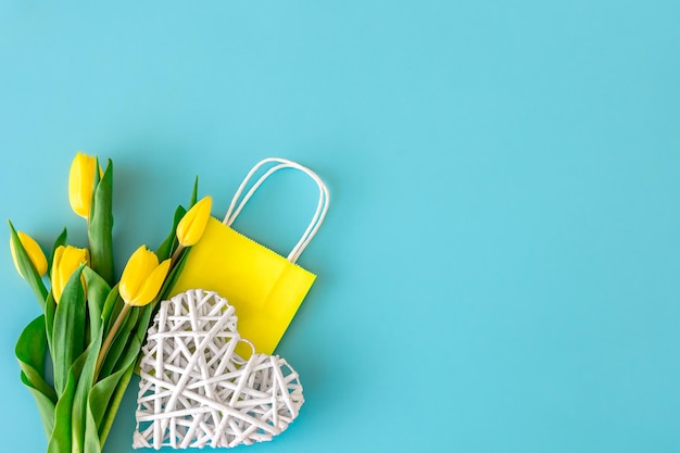 Flat lay blue background with flowers and paper bags