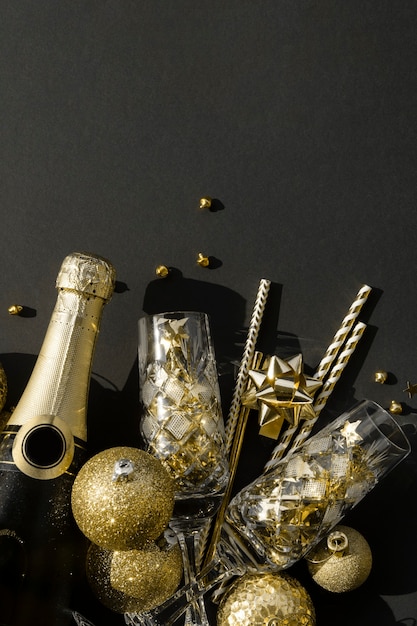 Flat lay of a bottle of champagne with crystal glasses confetti and baubles