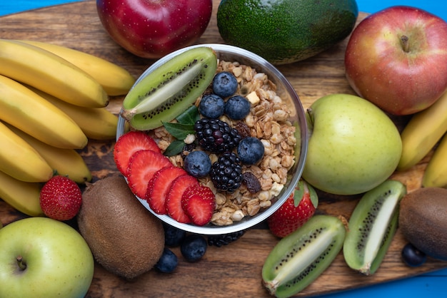 Flat lay of bright assorted fruits, bananas, apples, mangoes, kiwi, strawberries, blueberries, with cereals for a healthy Breakfast