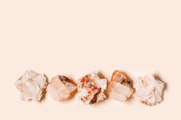 Flat lay bright beige quartz crystals on peach color background Magic and healing crystal gem stone