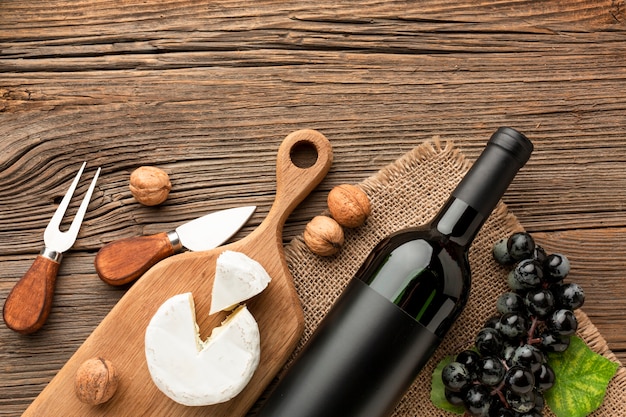 Flat lay camembert on wooden cutting board grapes and walnuts with ustensils