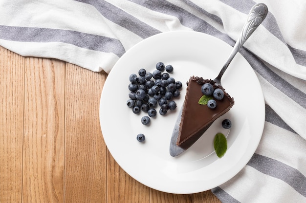 Flat lay of chocolate cake slice on plate with blueberries