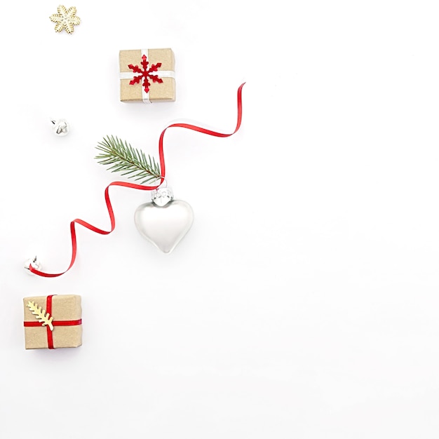 Flat lay Christmas composition on white background with holiday gift boxes, a heart-shaped toy and fir branches. Concept christmas, minimalism, holiday, sale.