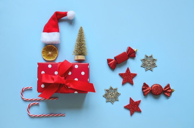 Flat lay of Christmas tree made from colorful decorations against blue background. Top view. Card